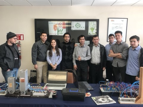 Student project exposition with electronics benches and trainers.